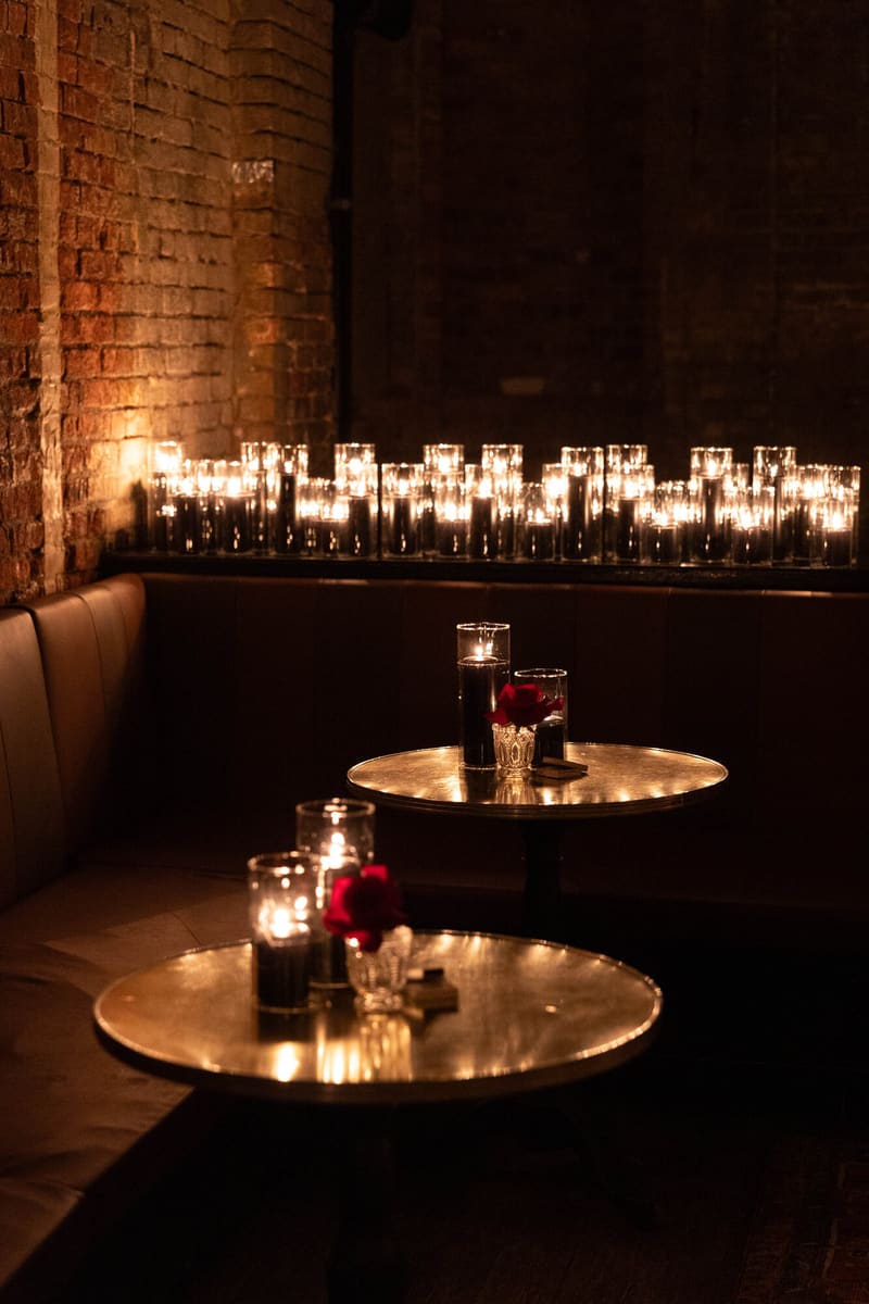 Black taper candles and red roses against brick