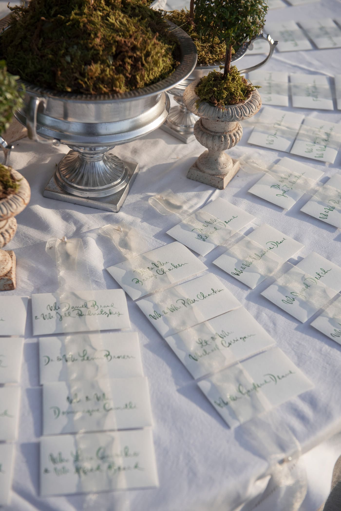 Calligraphed escort envelopes among moss-filled silver urns