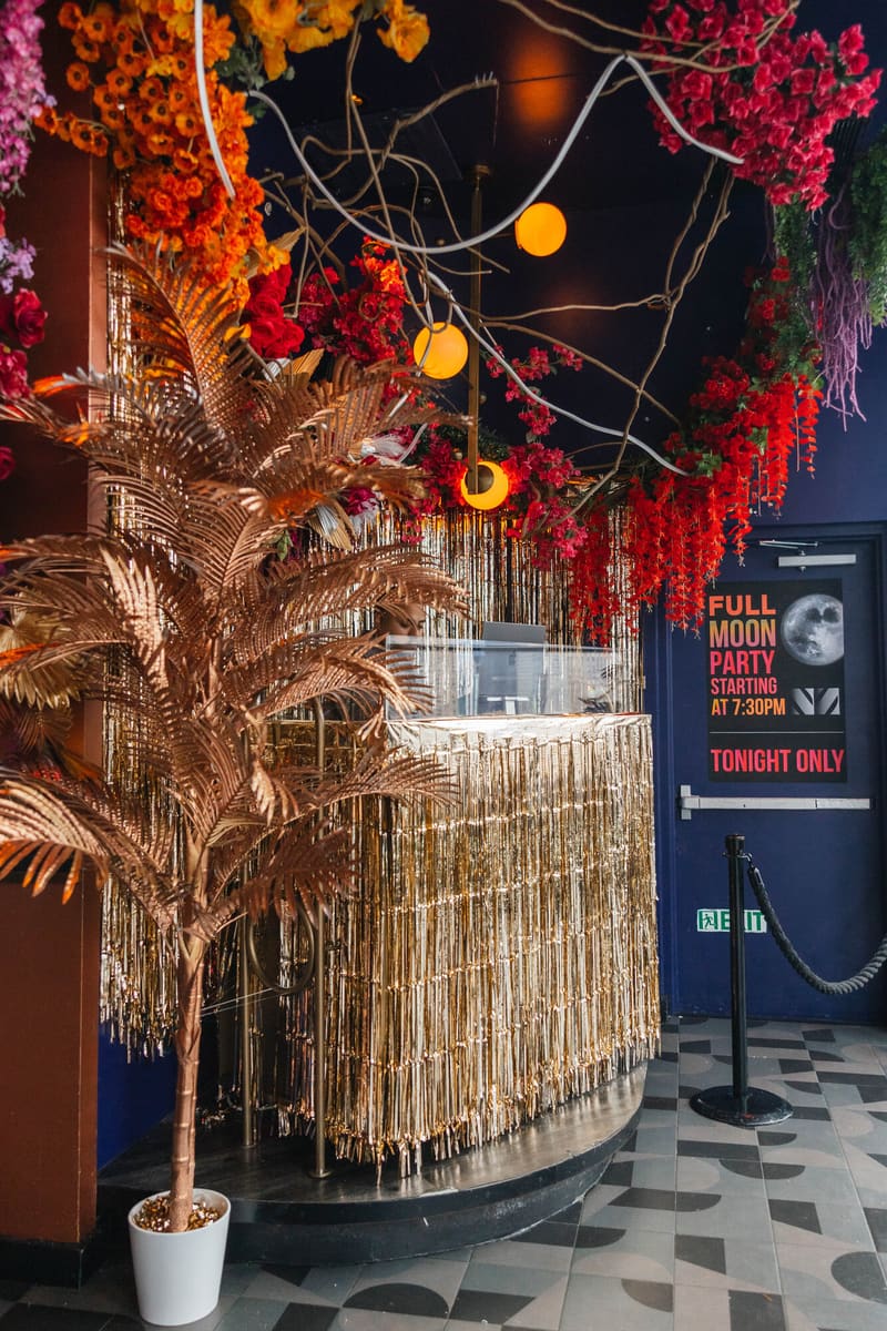 A welcome desk in gold fringe beneath hanging flowers