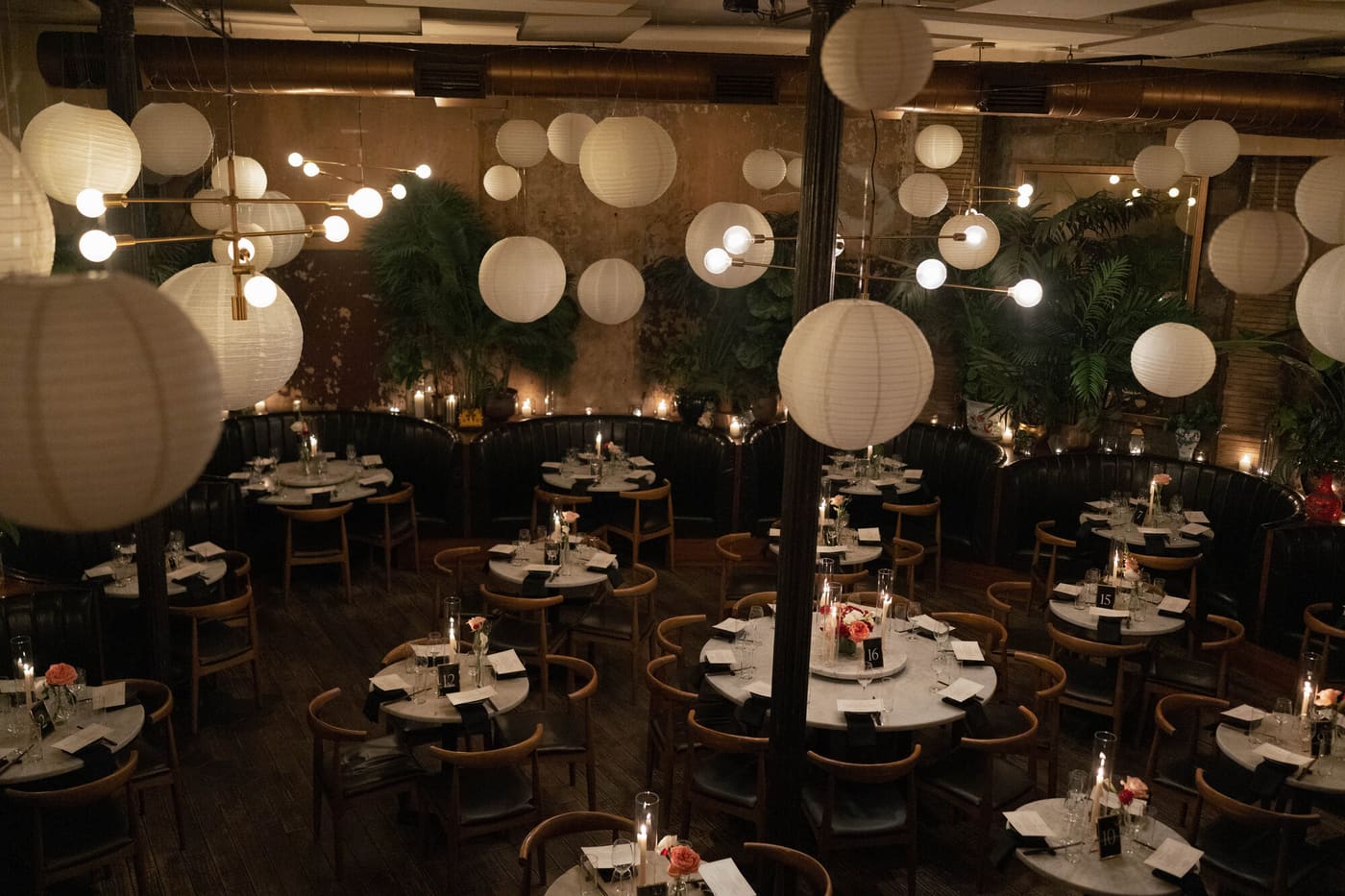 A dining room of round tables under a ceiling of paper lanterns