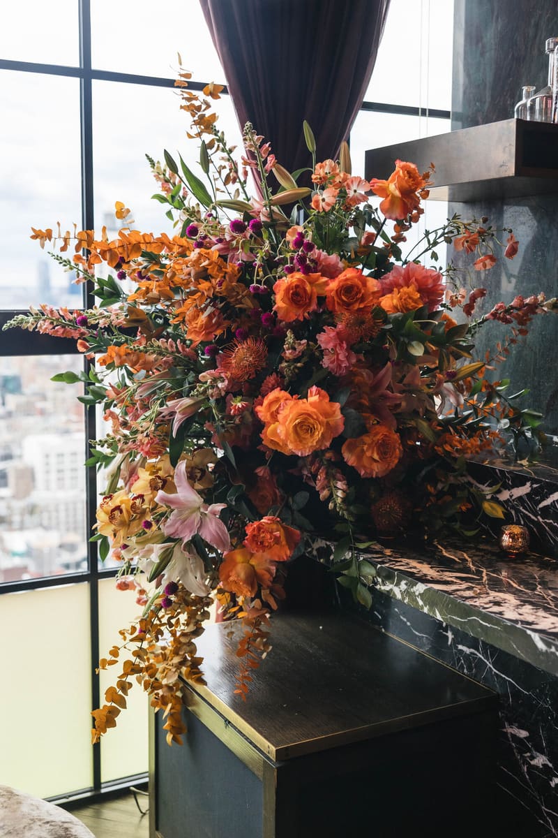 An orange and pink arrangement spilling across a marble bar