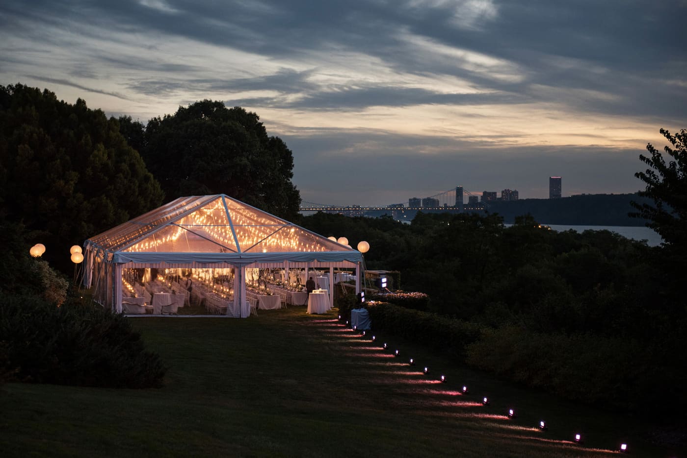 A glowing tent at dusk with the skyline beyond