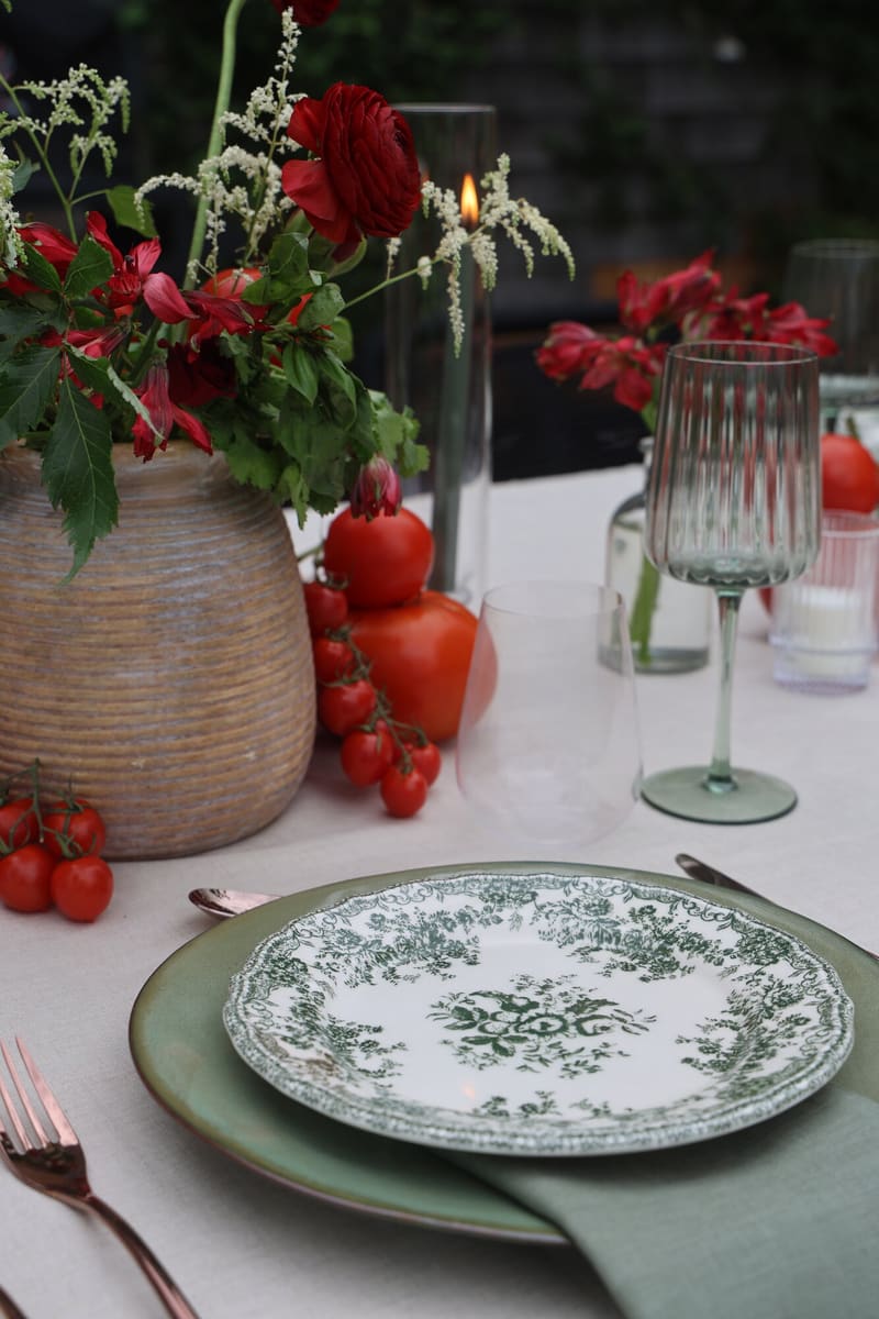 A green and white place setting with garden tomatoes and flowers