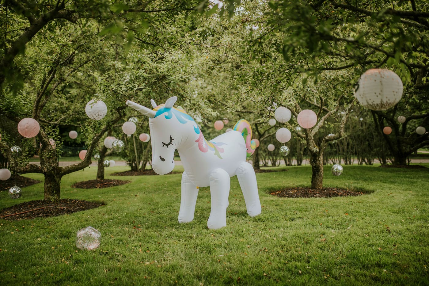 An inflatable unicorn among lantern-hung orchard trees