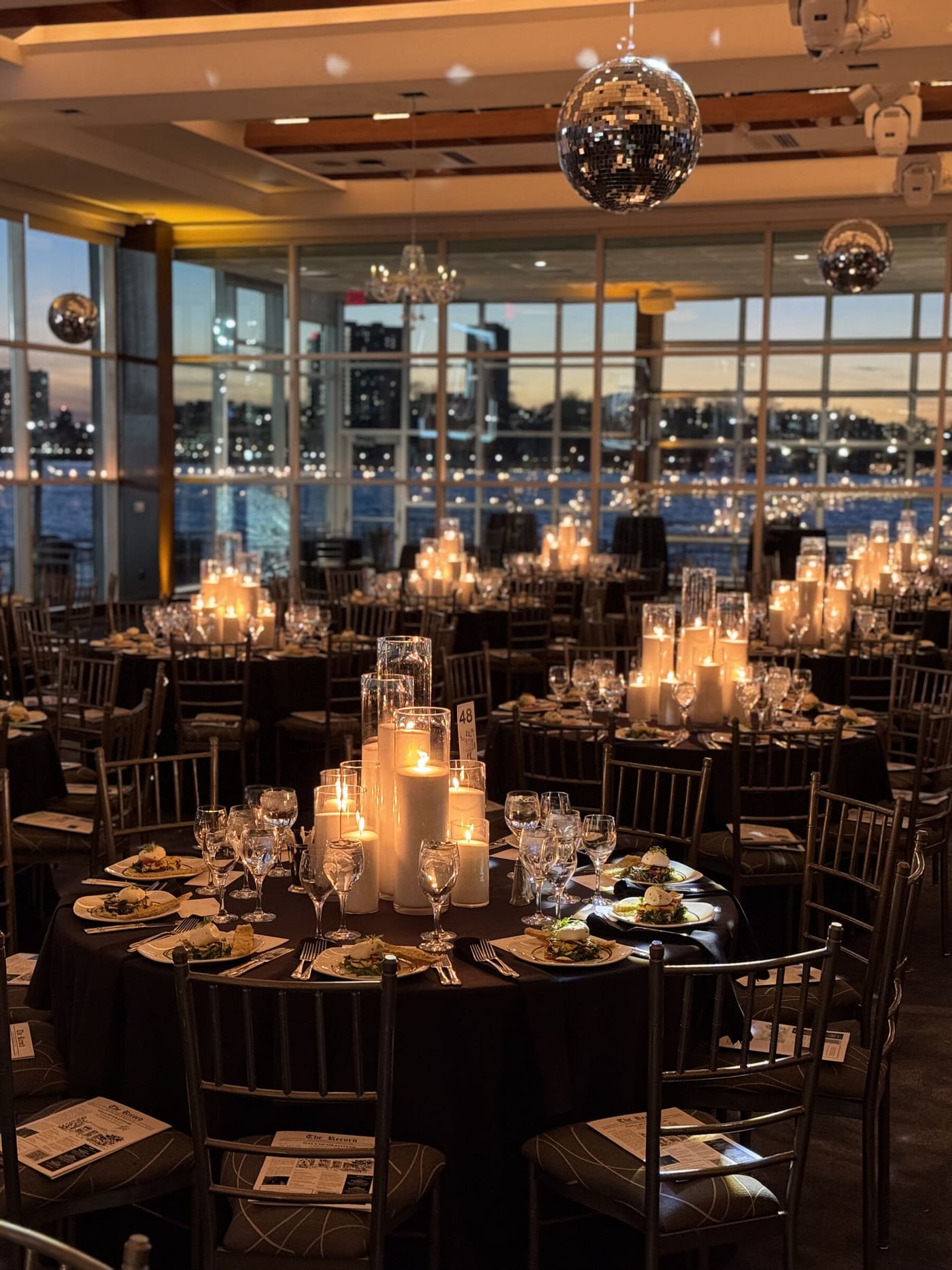 A waterfront ballroom at dusk, disco balls and candlelight